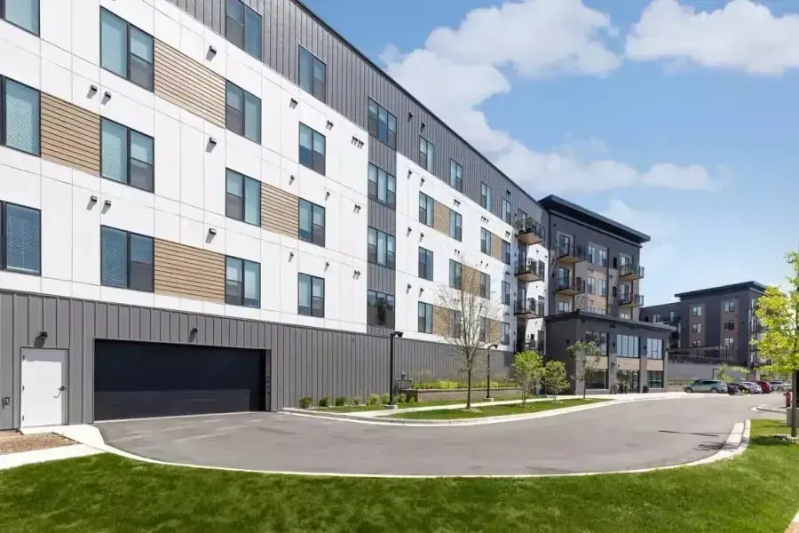 Modern multi storey apartment building with landscaped grounds and a garage entry